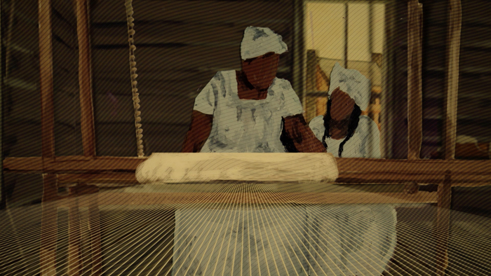 A screenshot from the animated film. A woman and a young child sit at a counterbalance loom.
